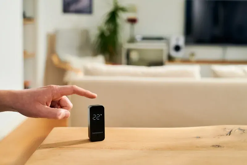 Een vinger tikt op de bovenkant van de HomeWizard Temperature Humidity Meter