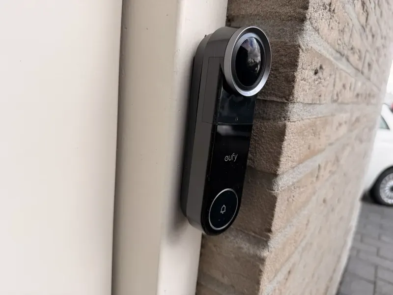 Eufy Video Doorbell S4 van opzij, de lens steekt uit langs de bakstenen hoek